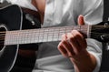 Close-up of hands of a young man playing guitar on a black background. Musical instrument, art concept. Royalty Free Stock Photo