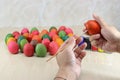 Close up hands of young person coloring eggs against paintbrush preparing easter day.