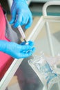 Close-up hands of young woman doctor anesthesiologist dressed in pink gown, blue gloves prepares solution for anesthesia Royalty Free Stock Photo