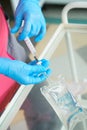 Close-up hands of young woman doctor anesthesiologist dressed in pink gown, blue gloves prepares solution for anesthesia Royalty Free Stock Photo