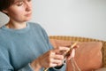 Close up hands of young woman knits with knitting needles sitting on chair at home. Knitting, hobby and handmade concept Royalty Free Stock Photo