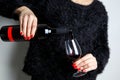 Close up of the hands of a young woman pouring red wine into a glass from a bottle Royalty Free Stock Photo