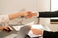 Close up of handshake of man and woman being business partners. Documents on blurred background