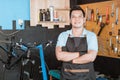 close up of handsome bicycle mechanic in smiling apron holding bicycle with crossed hands