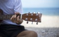 Close up handsome man playing classic guitar sitting on the beach in vacations Royalty Free Stock Photo