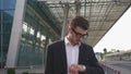 Close-up of handsome nervous businessman in glasses waiting for his retarded flight. Modern airport background