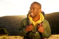 Close up handsome young african american man with backpack smiling with sunrise in background Royalty Free Stock Photo