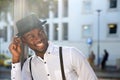 Close up handsome young african american man with suspenders and hat smiling in city Royalty Free Stock Photo