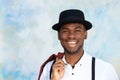 Close up handsome young african american man with suspenders and hat smiling by wall Royalty Free Stock Photo