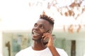 Close up handsome young black man standing outside and talking on cellphone Royalty Free Stock Photo