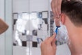 Close up of handsome young man shaving with a razer in bathroom Royalty Free Stock Photo
