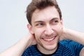 Close up handsome young man smiling with hands behind head by white wall Royalty Free Stock Photo