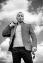 Close-up of handsome young man wearing suit jacket, sunglasses and looking away while standing against cloudy sky. Mr Royalty Free Stock Photo