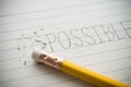 Close up handwriting impossible change to possible via pencil eraser on notepad background. Royalty Free Stock Photo