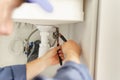 Close up of professional plumber repairing a siphon pipe with adjustable wrench on the kitchen