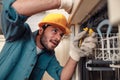 Close up of handyman in special clothing repairing dishwasher in modern kitchen Royalty Free Stock Photo