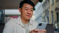 Close-up happy asian man holding mobile phone browsing social network male tourist booking ticket using smartphone sends Royalty Free Stock Photo