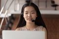 Close up happy asian woman wearing headphones, consulting client online.