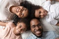 Close up happy black family of four laying on bed. Royalty Free Stock Photo