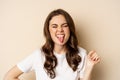 Close up of happy, carefree beautiful woman posing silly, showing tongue, having fun, standing in casual white t-shirt Royalty Free Stock Photo