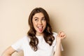 Close up of happy, carefree beautiful woman posing silly, showing tongue, having fun, standing in casual white t-shirt Royalty Free Stock Photo