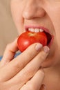 Close up happy Caucasian woman biting a raw red tomato. Three-quarter front view. Low angle view. Vertical frame Royalty Free Stock Photo