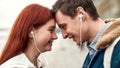 Close up of happy couple of teenagers listening to music using the same pair of earphones, looking at each other with Royalty Free Stock Photo
