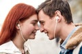 Close up of happy couple of teenagers listening to music using the same pair of earphones, looking at each other with Royalty Free Stock Photo