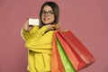 Close-up of happy exited brunette woman with glasses holding credit card and colorful shopping bags, looking at camera Royalty Free Stock Photo