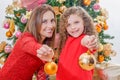 Close up of happy girl decorating Christmas tree with her mom pointing in front of them golden christmas balls, family Royalty Free Stock Photo