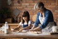 Close up happy grandmother with little granddaughter rolling out dough