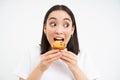 Close up of happy korean woman eating cupcake, delicious dessert, smiling from pleasure, white background