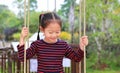 Close up happy little Asian child girl play and sitting on the swing in the nature park Royalty Free Stock Photo