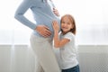 Happy little girl embracing her pregnant mother belly Royalty Free Stock Photo