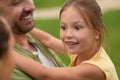 Close up of happy little girl looking aside while her dad holding her, spending time with family outdoors on a warm day Royalty Free Stock Photo