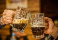 Close up of a happy male friends clinking with beer mugs in pub Royalty Free Stock Photo