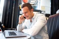 Close up happy man sitting at cafe with laptop and talking on mobile phone Royalty Free Stock Photo