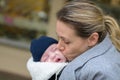 Close up of a happy mother in her 40s holding her newborn baby in a baby carrier and kissing it lovingly Royalty Free Stock Photo