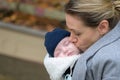 Close up of a happy mother in her 40s holding her newborn baby in a baby carrier and kissing it lovingly Royalty Free Stock Photo