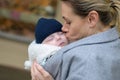 Close up of a happy mother in her 40s holding her newborn baby in a baby carrier and kissing it lovingly Royalty Free Stock Photo