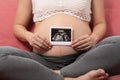 Close up Happy Pregnant Woman holding ultrasound image stroking big belly with love  on couch,Pregnancy of young woman Royalty Free Stock Photo