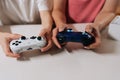 Close-up of happy relaxed couple holding using white and blue wireless controllers, engaging in gaming session sitting Royalty Free Stock Photo