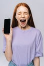 Close-up of happy screaming young woman in casual clothes showing phone with black empty screen. Royalty Free Stock Photo