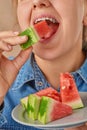 Close-up of a happy smiling Caucasian woman holding a slice of watermelon with her hand and biting it. Front view. Low angle view Royalty Free Stock Photo