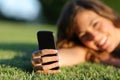 Close up of a happy teen girl hand using a smart phone on the grass