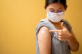 Close up of happy teens girls and wear a mask in the shoulder with plaster on arm after vaccination on yellow studio background,