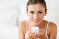 Close up of happy woman holding cream jar