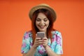 Close up of happy woman in straw hat smiling, holding smartphone and watching social media or typing message, isolated Royalty Free Stock Photo