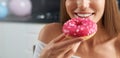 Happy woman tasting colorful donut at home