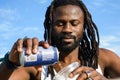 close up of happy young African man with beard and dreadlocks outdoors serving beer in plastic cup